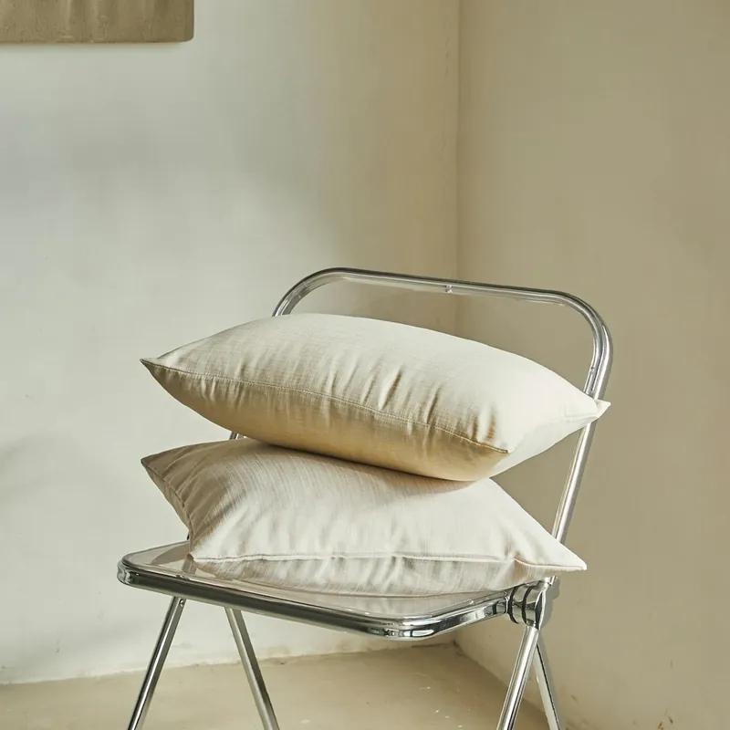 Deux coussins couleur sable empilés sur une chaise pliante transparente